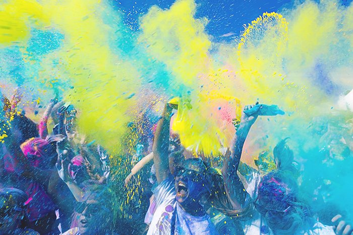 Foto de una multitud en un festival con polvo de color amarillo y azul arrojado al aire