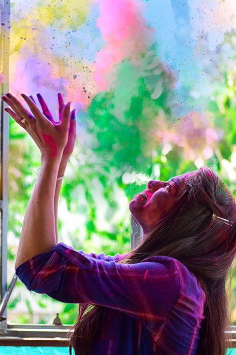 Foto de vista lateral de una chica arrojando polvo de colores del arco iris en el aire, velocidad de obturación rápida 