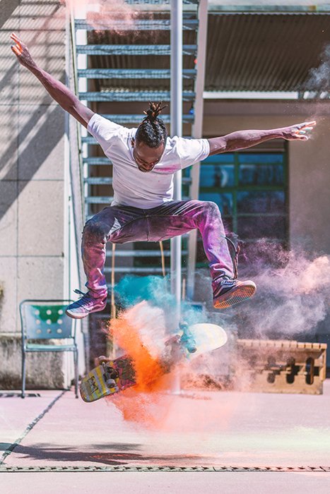 Foto de un hombre haciendo un truco de skate con polvo de color naranja