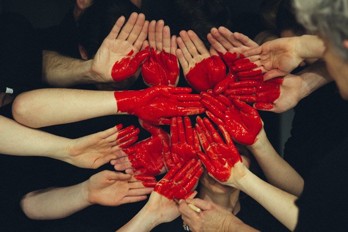 Foto de muchos pares de manos pintadas de rojo formando la forma de un corazón