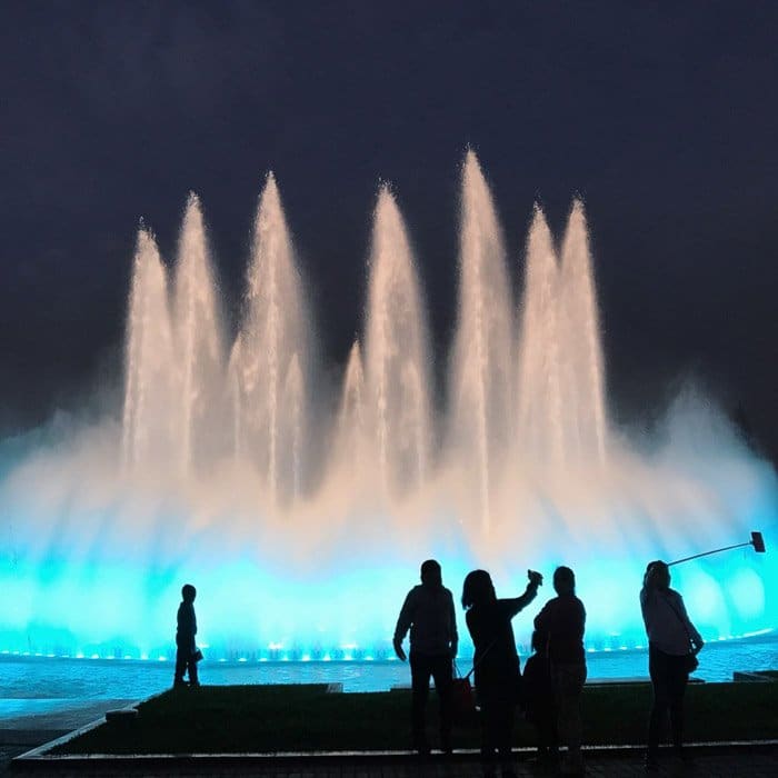 Fotografía con poca luz de una hermosa fuente en la noche con siluetas de personas en primer plano