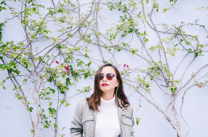 Fotografía de smartphone de una niña con gafas de sol contra una pared blanca. 