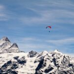 un parapente navegando sobre montañas cubiertas de nieve - habilidades de fotografía de aventuras