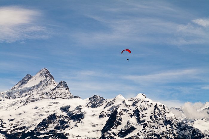 un parapente navegando sobre montañas cubiertas de nieve - habilidades de fotografía de aventuras