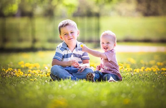 Una foto de dos niños felices jugando entre sí en la hierba.