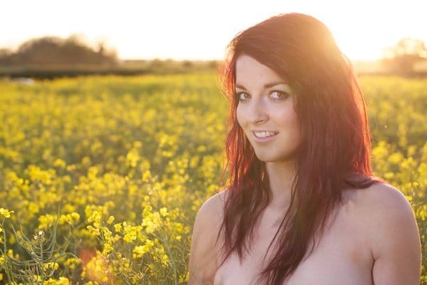 Foto sin editar de una mujer joven en el campo de flores amarillas