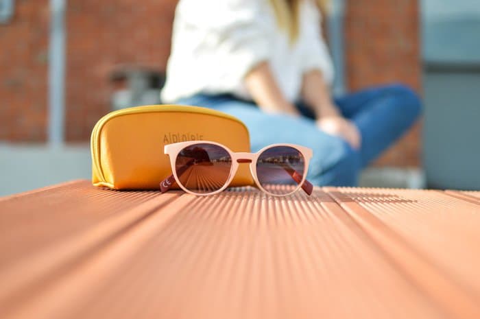 Una foto de producto de gafas de sol y estuche sobre una mesa de madera