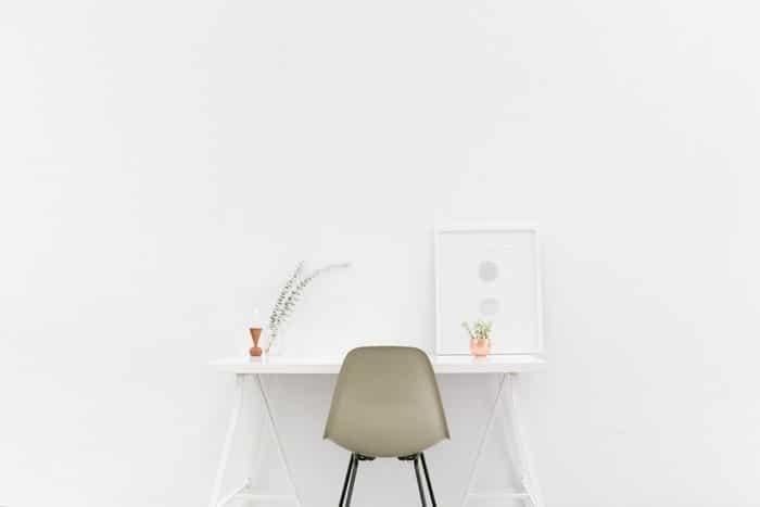 Una silla y un escritorio frente a un fondo blanco.