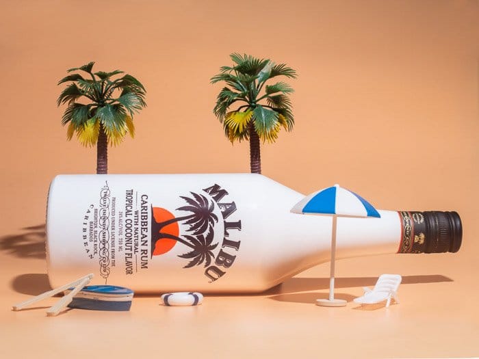 Una foto de producto de una botella de Malibu en una pequeña escena de playa