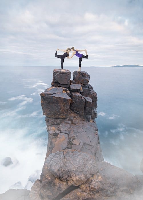 Imagen de fotografía compuesta de mujeres en una pose de yoga en la cima de acantilados rocosos junto al agua