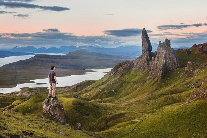 Un hombre de pie sobre una roca con un magnífico paisaje detrás 