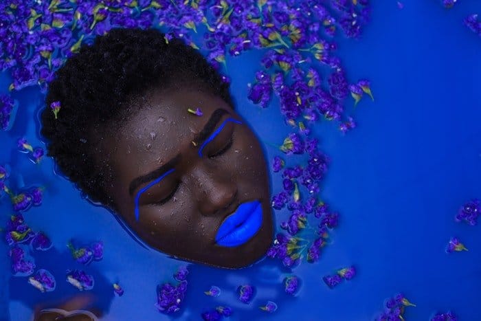 Rostro de mujer con maquillaje azul en agua azul