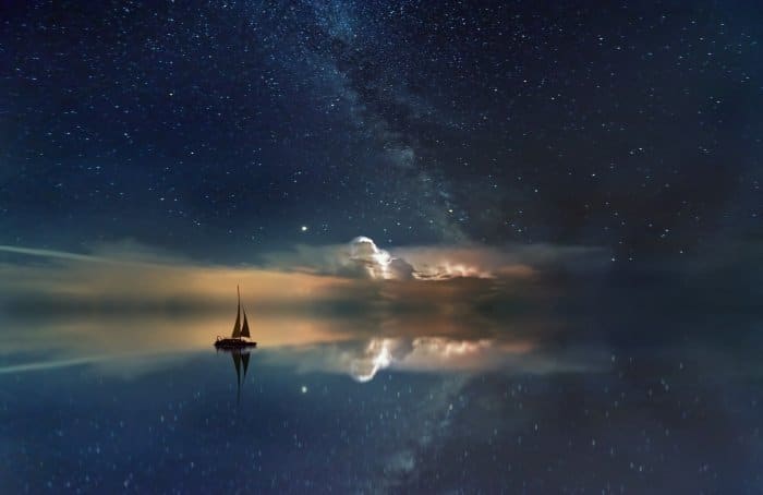 Una imagen editada de un velero flotando en el mar con un cielo estrellado.