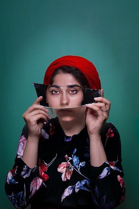 Un colorido retrato de una modelo femenina sosteniendo un espejo en su rostro - ideas de fotografía conceptual 