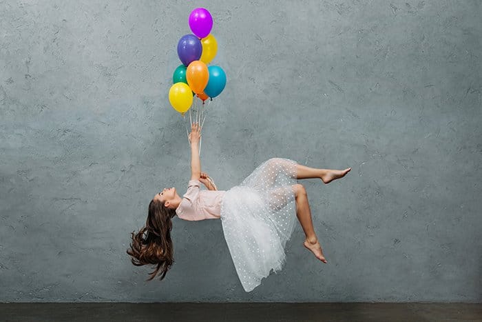Mujer joven levitando con globos.