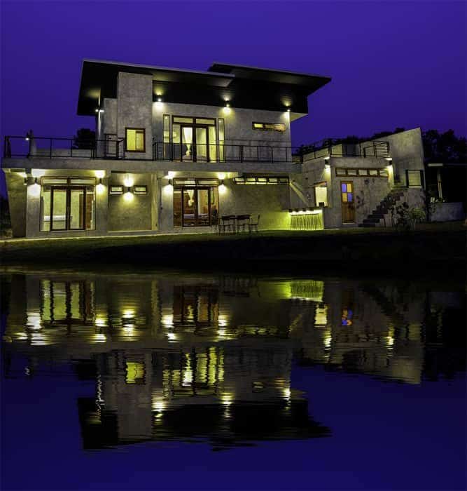 Impresionante foto arquitectónica de una casa al anochecer con un fresco reflejo de Photoshop en el agua debajo
