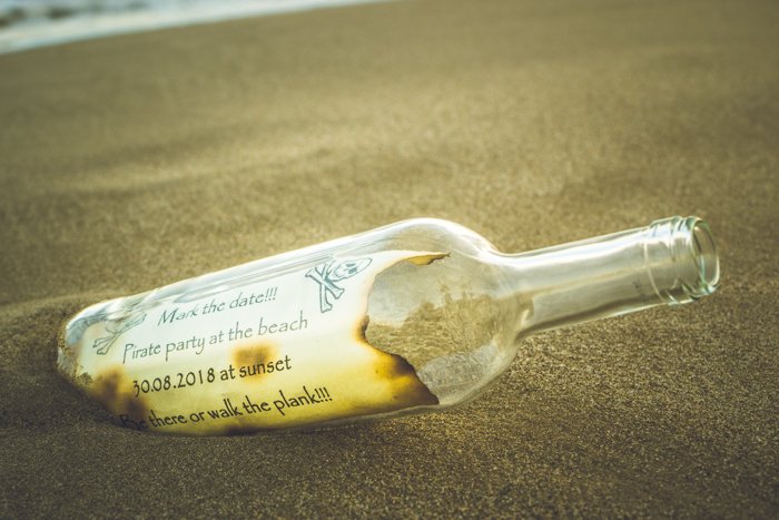 Una nota pirata dentro de una botella en la arena: ideas geniales para fotografías de playa
