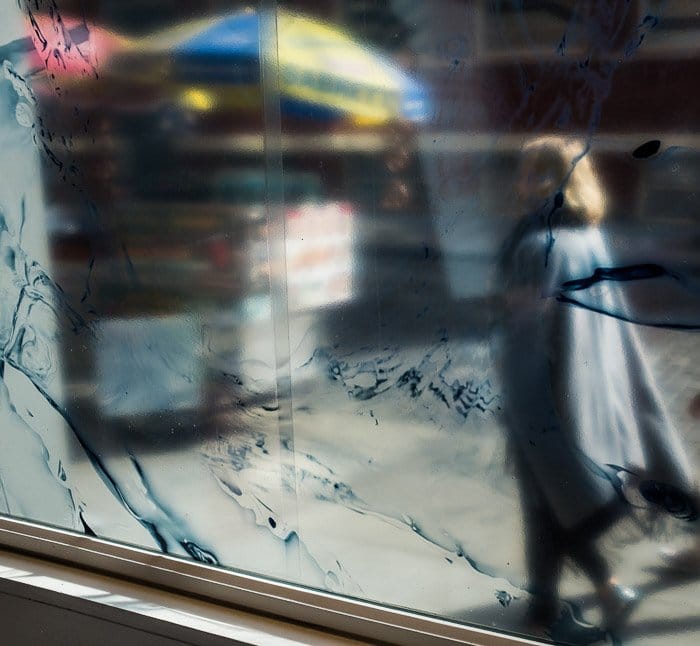 Un transeúnte reflejado en una ventana de la calle.  Fotocromía.