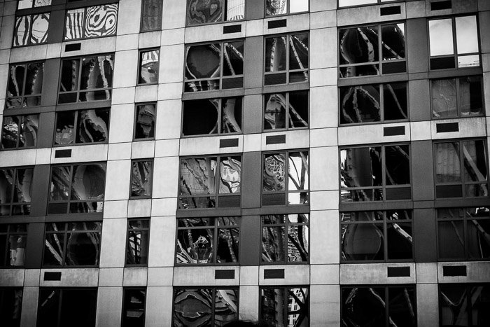 Reflejos distorsionados en las ventanas de un edificio de gran altura.  Fotografía urbana de la calle.  Reflexiones monocromáticas.