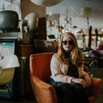 un retrato de una niña sentada en un sillón en una tienda de segunda mano