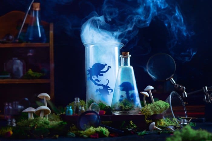 Naturaleza muerta mística con botellas de vidrio con las siluetas de pequeños personajes recortados en el interior y humo saliendo