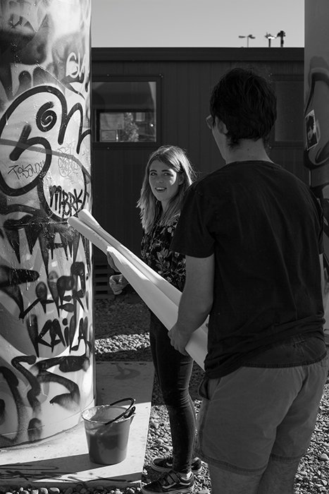 Fotografía en blanco y negro de artistas de CHUZKOS instalando una exposición fotográfica de arte callejero.  Fotografía callejera creativa