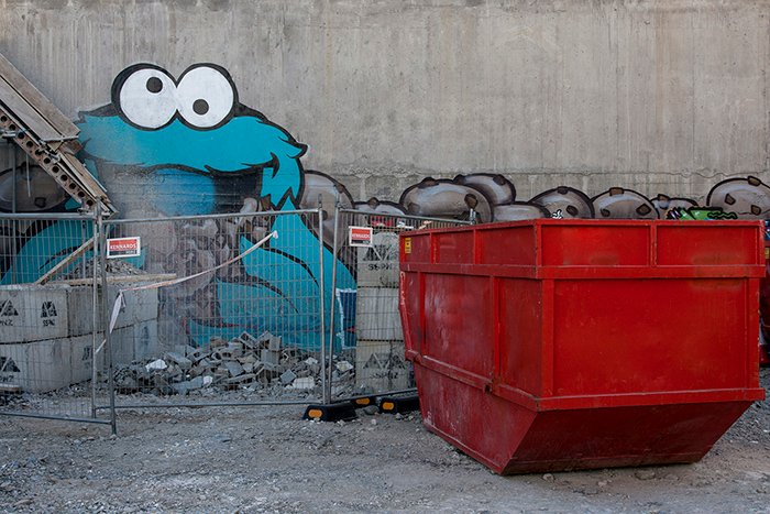 Graffiti del personaje del monstruo de las galletas en una pared detrás de un sitio en construcción.  Fotografía callejera creativa