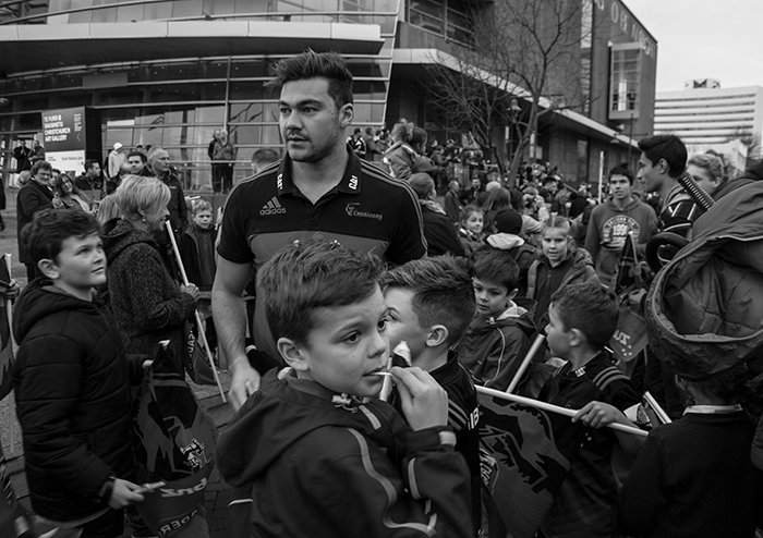 Fotografía callejera blanca y negra de una multitud que rodea a su equipo ganador de rugby.