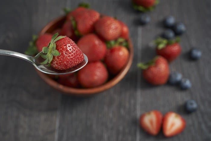 Imagen de fotografía de alimentos con sensor de fotograma completo de fresas y arándanos con una mesa y un fondo borrosos
