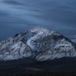 Un pico de montaña nevado con un cielo oscuro.