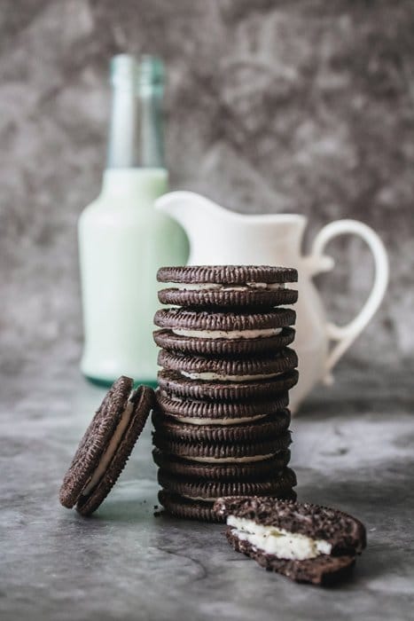 Una pila de galletas de chocolate delante de una jarra de leche.