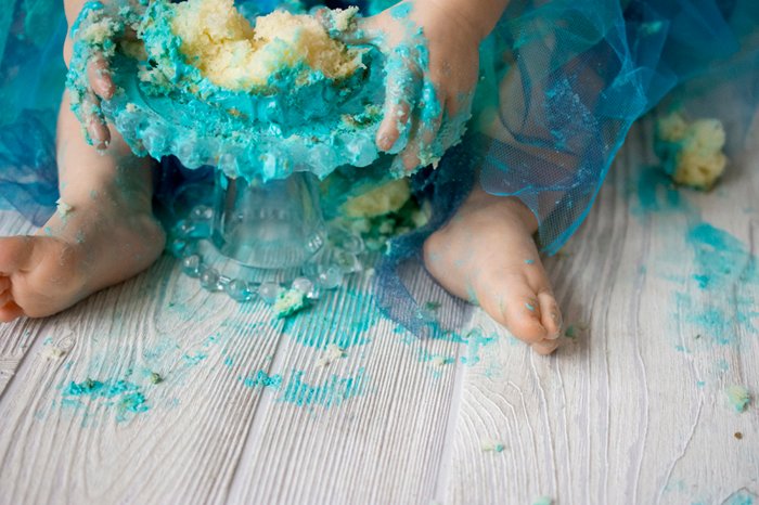 Los pies de un bebé cubiertos con glaseado verde - Cake Smash Photography