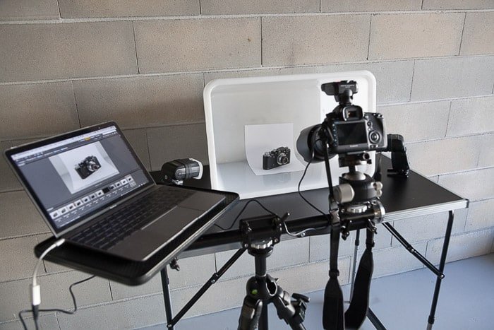 Una configuración de sesión de fotos de bricolaje que contiene una computadora portátil, un difusor de flash de caja blanca bricolaje, una cámara réflex digital en un trípode