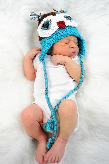 Un dulce retrato cenital de un bebé con un sombrero novedoso sobre una manta blanca