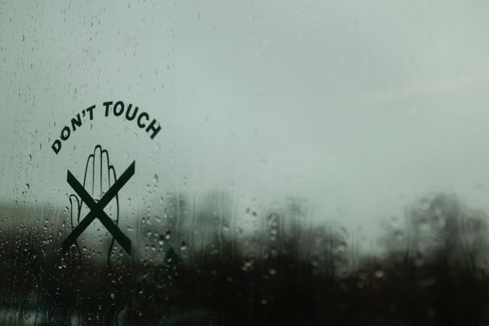 Un letrero de 'no tocar' en una ventana lluviosa - accesorios para fotomatón