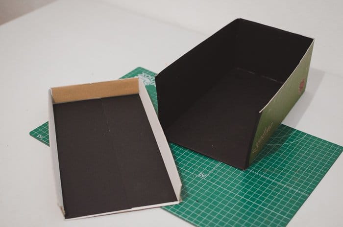 Pegar papel negro a una caja de zapatos para hacer un proyector de bricolaje