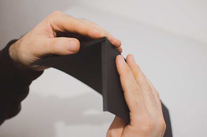 Una persona doblando papel negro para hacer un proyector de lente de teléfono de bricolaje