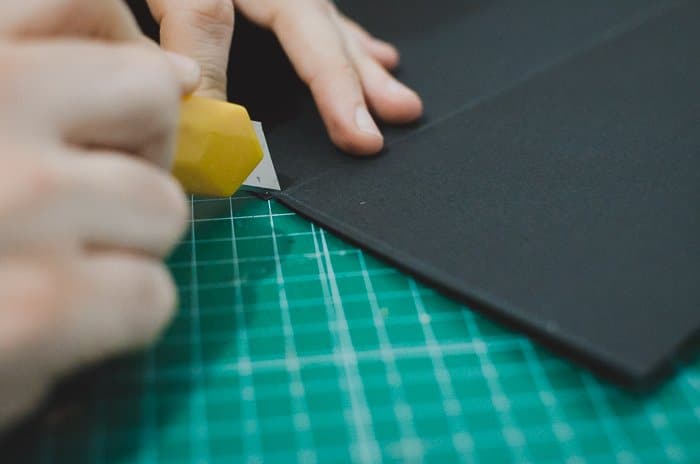 Una persona cortando cartón para hacer un proyector de teléfono de bricolaje