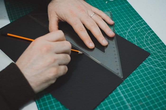 Una persona cortando cartón para hacer un proyector de teléfono de bricolaje