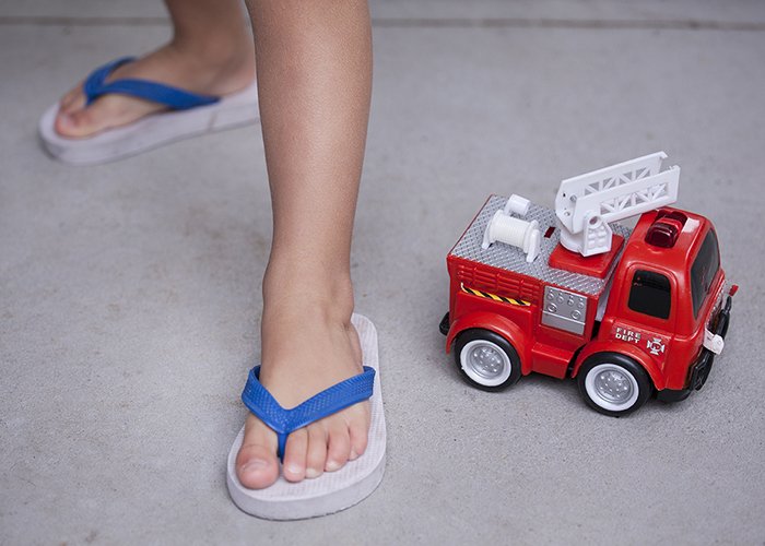 un primer plano de los pies de un niño junto a un camión de juguete
