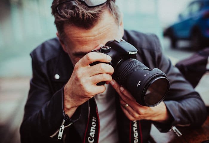Un fotógrafo agachado para tomar una foto con su ojo dominante
