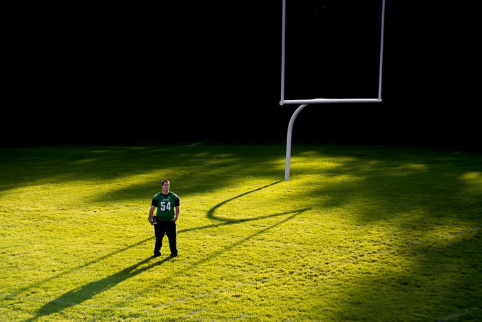 foto de un chico parado en medio de un campo de fútbol con una iluminación espectacular