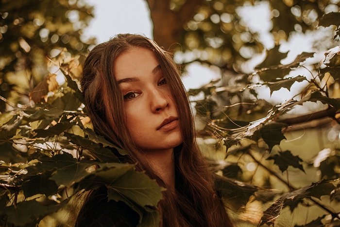Fotografía de ensueño de una modelo femenina posando al aire libre entre hojas - retratos etéreos 