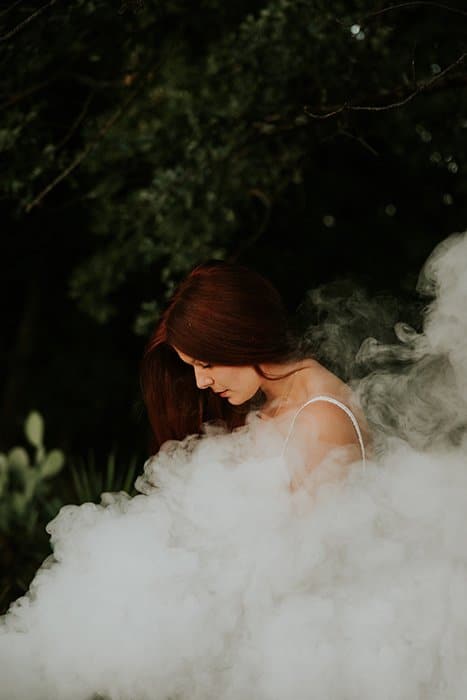 Retrato de ensueño de una modelo femenina posando al aire libre rodeada de humo y un fondo de ensueño