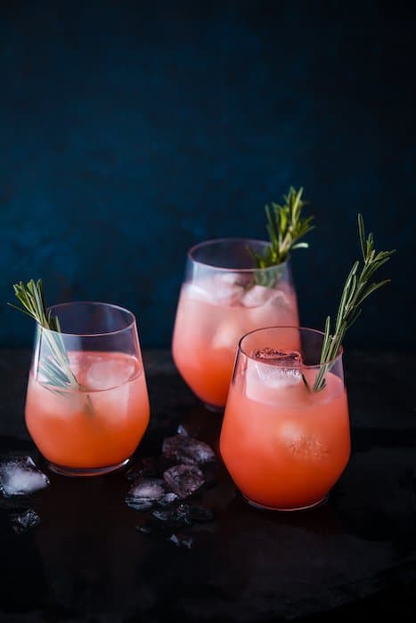 Foto de bebida elegante de tres cócteles de naranja contra un fondo oscuro