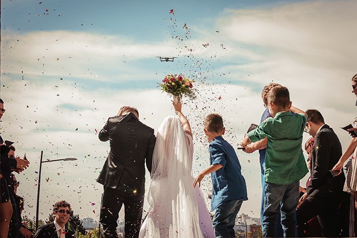 Foto de boda de la pareja casada y pétalos de flores en el aire.