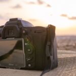Una cámara de fotografía DSLR descansando sobre un paño en la playa