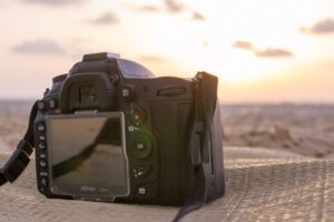 Una cámara de fotografía DSLR descansando sobre un paño en la playa