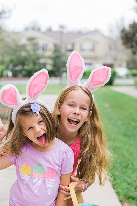 Dulce retrato de Pascua de dos niñas con orejas de conejo posando al aire libre