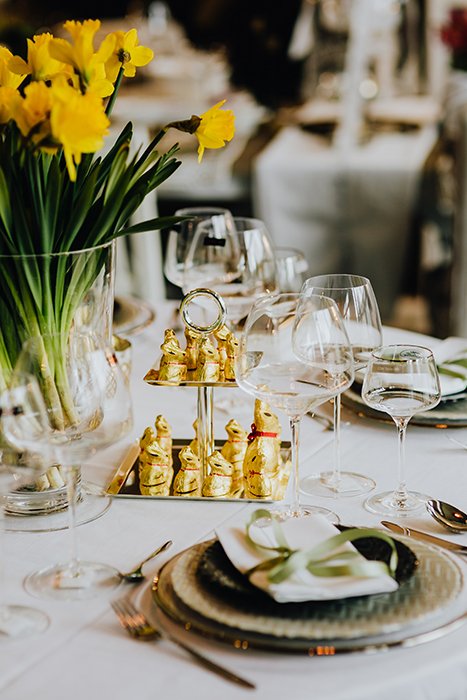 Amplio y luminoso Bodegón de Pascua de una mesa de comedor con tulipanes y conejitos de chocolate